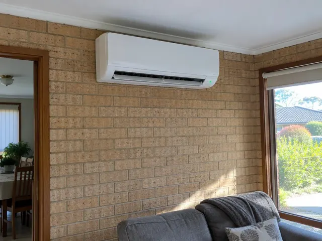 Wall-mounted split system running on a brick interior wall above a lounge in Modbury Heights